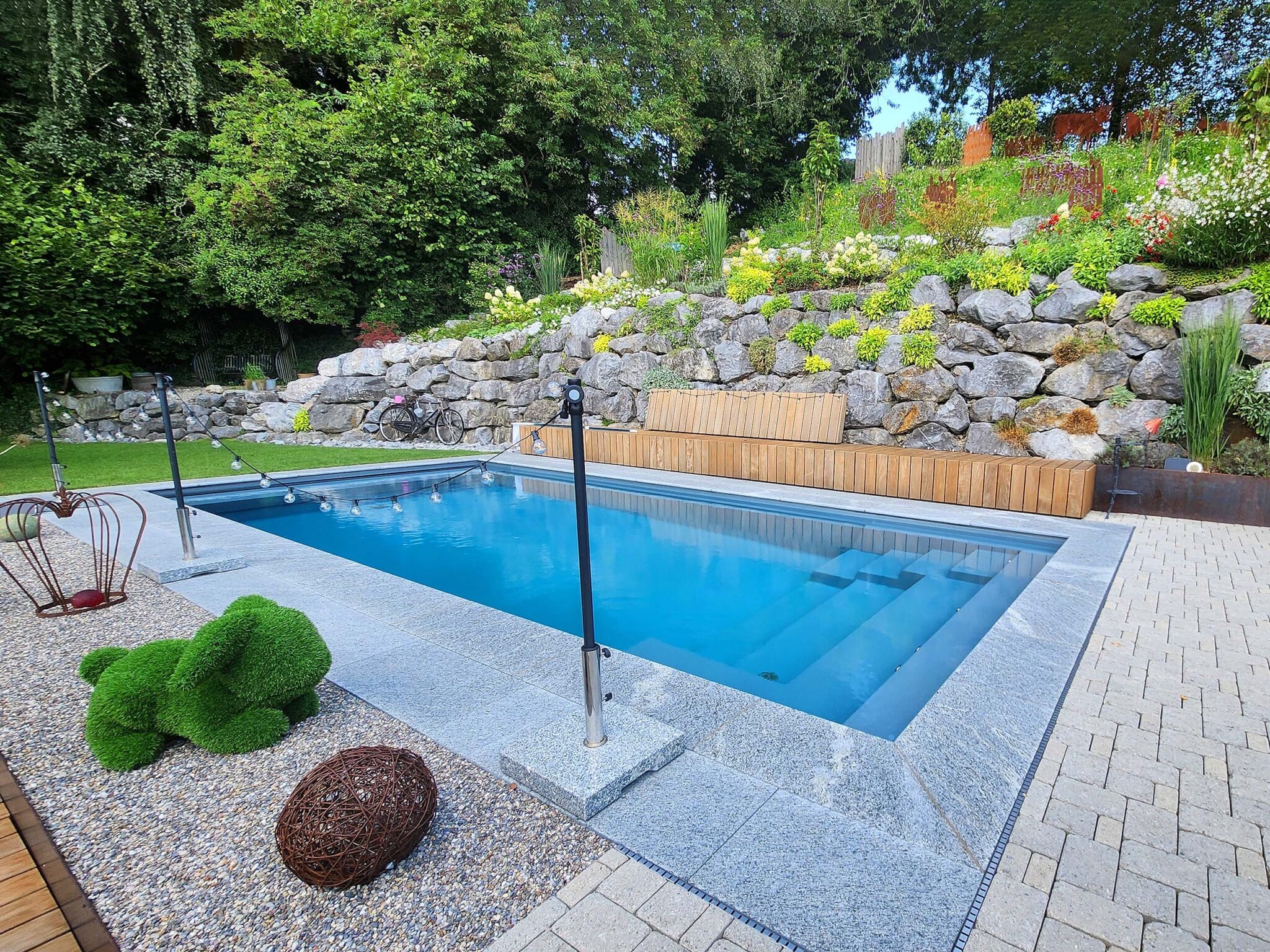 Fertiggestellter Poolgarten mit Natursteinmauer (derselbe Pool von gegenüberliegender Seite)
